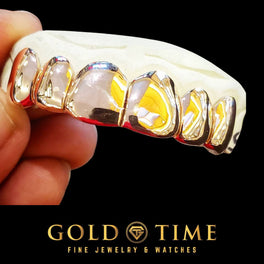 Rose gold solid grillz with perm cuts on a top dental mold held in hand