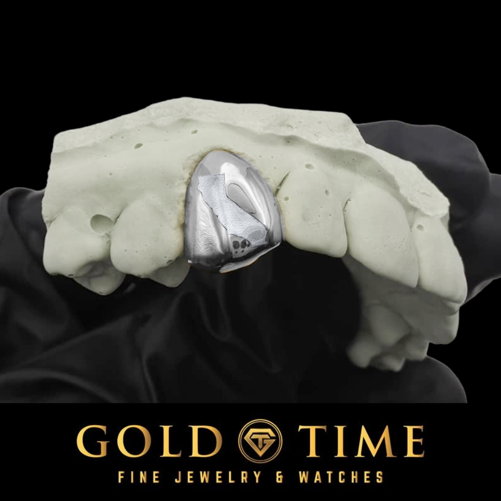 Silver single tooth grillz cap with a state engraving, fitted to a dental mold on a black background