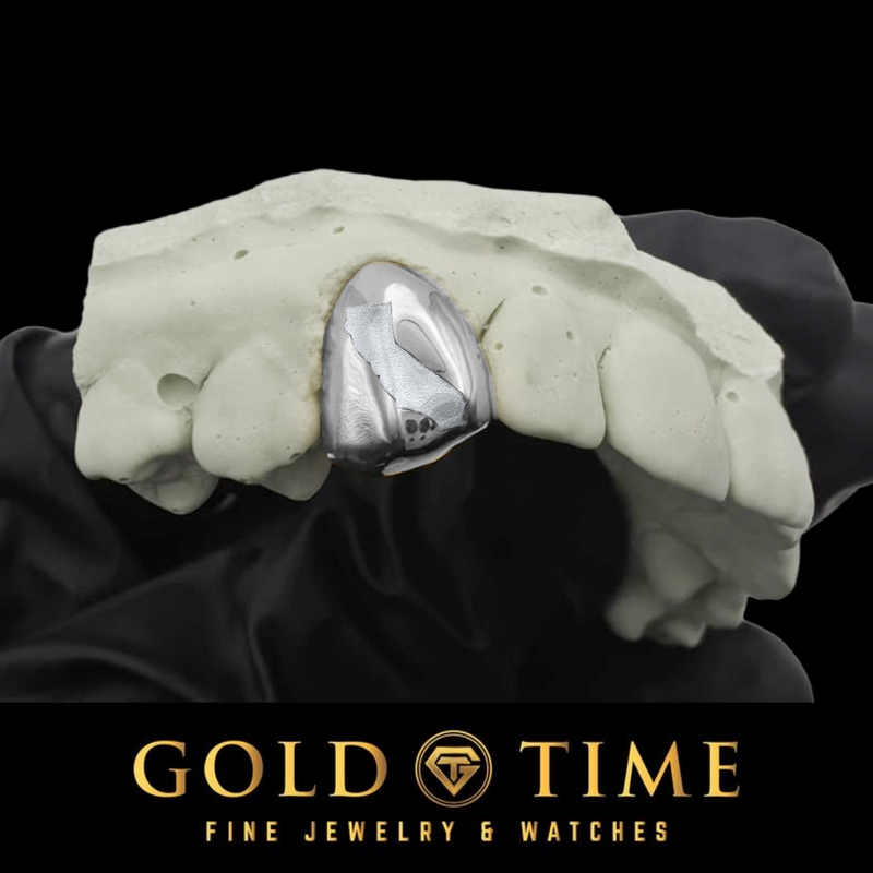 Silver single tooth grillz cap with a state engraving, fitted to a dental mold on a black background