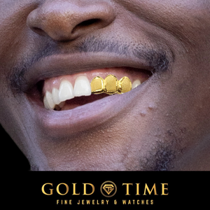 A close-up of a man's mouth wearing three gold grillz on his front teeth, with a black banner at the bottom reading 'GOLD TIME FINE JEWELRY & WATCHES'.