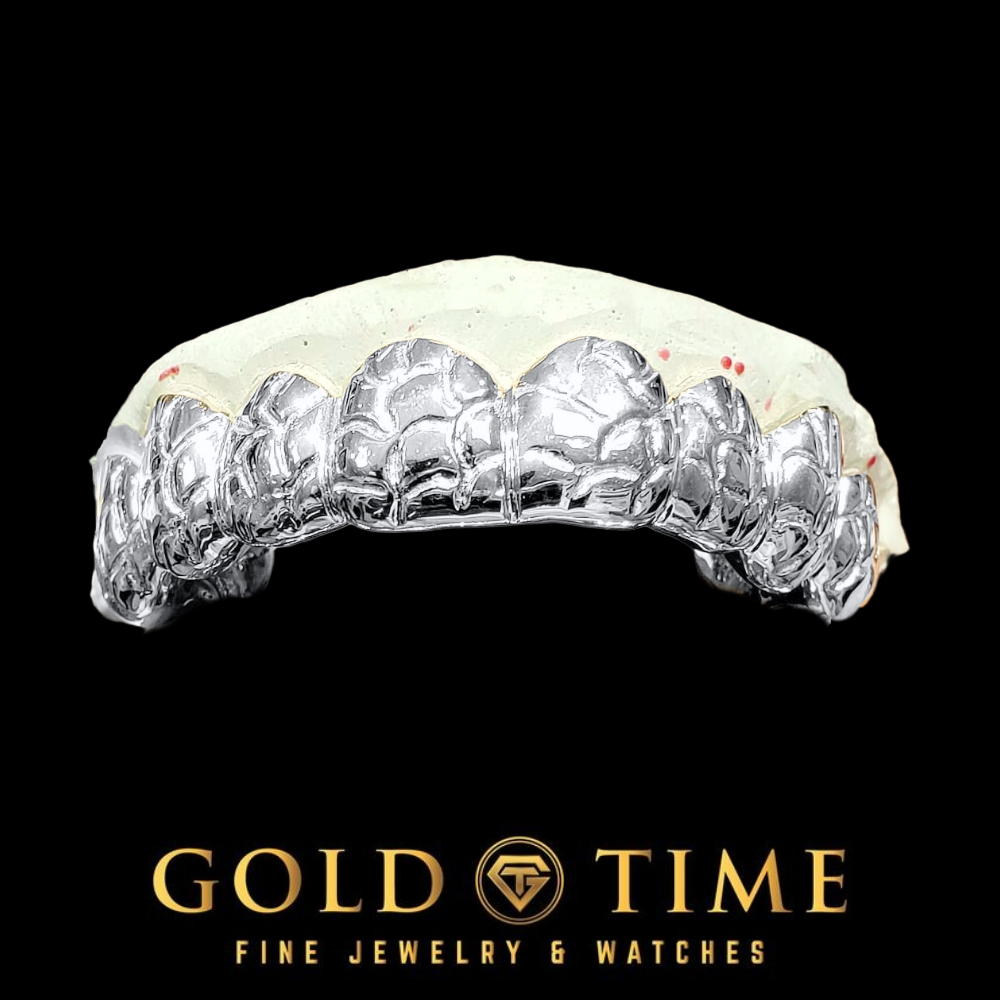 A custom silver dental grill on a white dental mold, displayed against a solid black background with the Gold Time logo at the bottom.