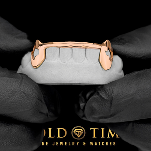 Rose gold 6 piece grillz with Texas cut out fangs and a solid tip bar on a dental mold held in gloved hands, Gold Time