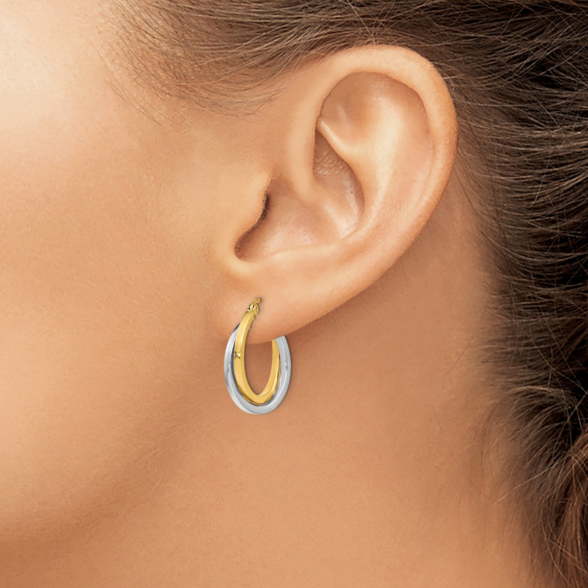 14K Two-Tone Gold Intertwined Double Hoop Earrings in yellow and white gold, worn on the ear