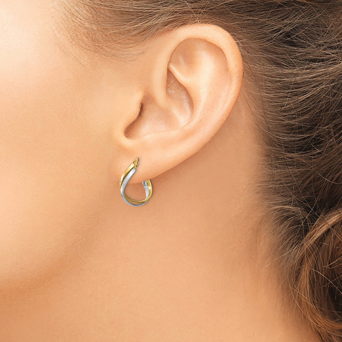 14K Two-Tone Gold Twisted Hoop Earrings in yellow and white gold, worn on the ear