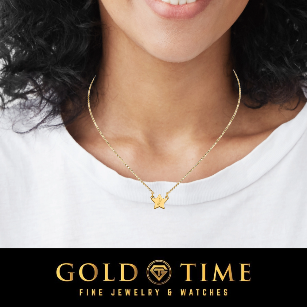A close-up of a woman wearing a delicate gold chain necklace with a small star-shaped pendant. The image is cropped from the lower face to the upper chest, showing a white t-shirt.