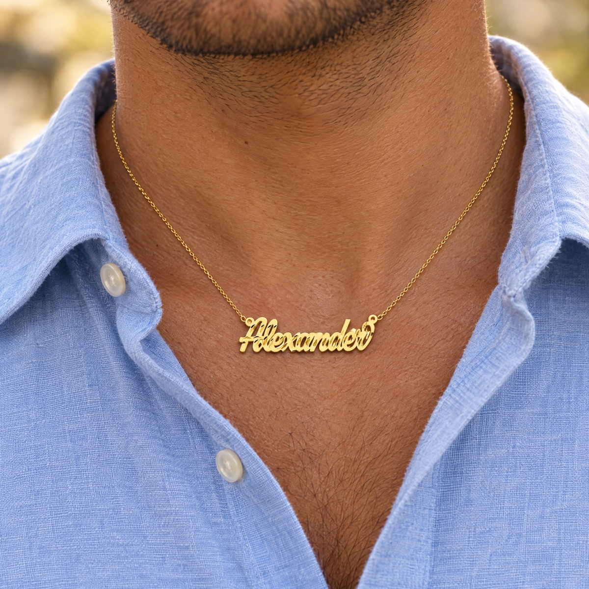 Yellow gold cursive nameplate necklace reading Alexander, worn by a man in an open collar shirt, lifestyle photo, Gold Time