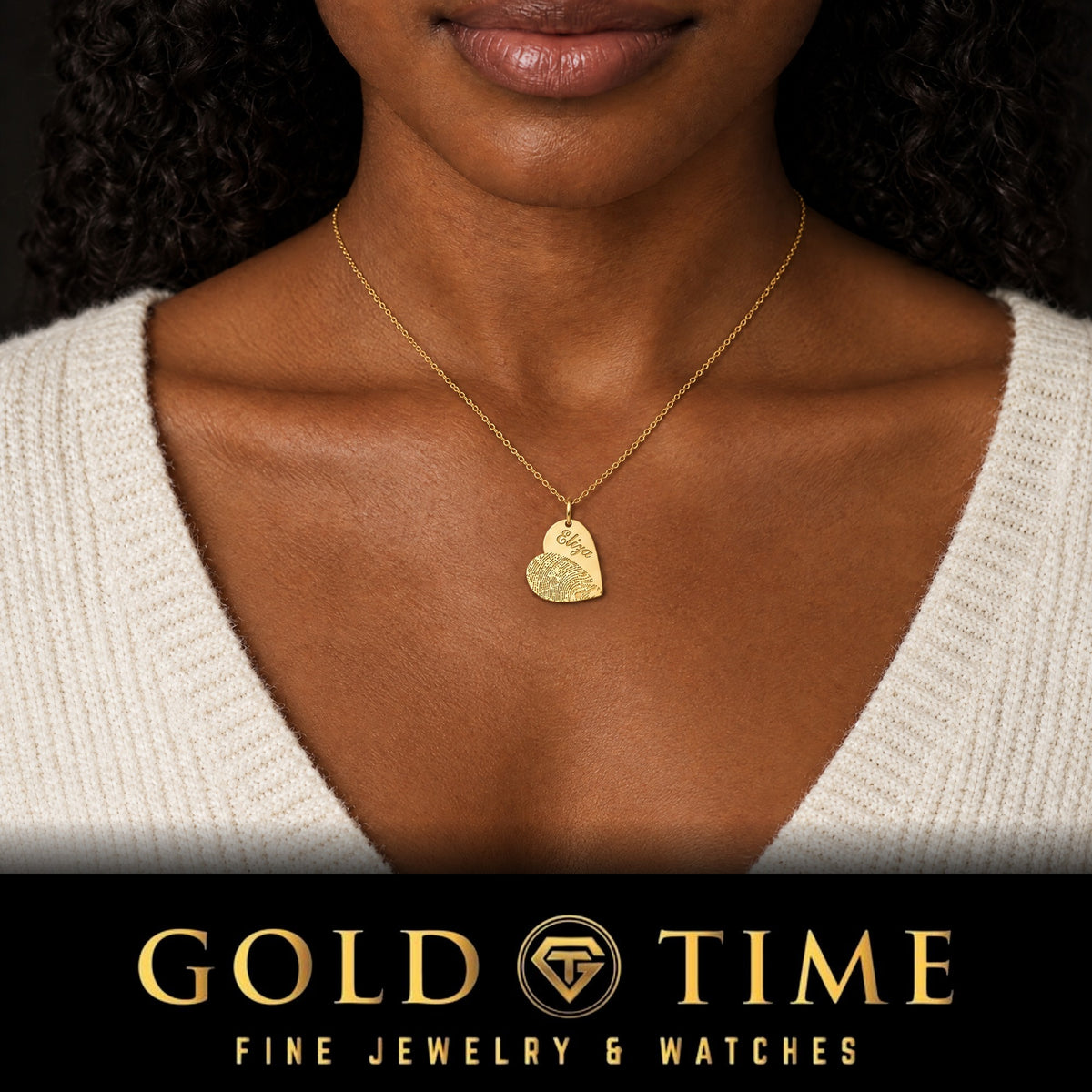 Woman in a cream sweater wearing the yellow gold fingerprint and name heart charm engraved Eliza, Gold Time