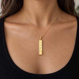 Yellow gold hieroglyphics cartouche bar pendant worn on a fine chain by a woman, lifestyle photo, Gold Time