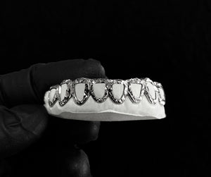 6 piece open face trillion cut grillz in white metal held on a dental mold