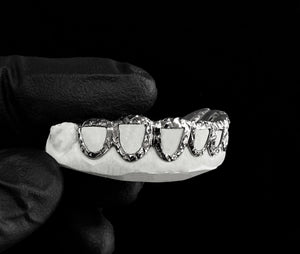 Angled view of white 6 piece open face trillion cut grillz on a mold