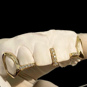 Angled view of the gold open face fang grillz on a dental model showing the stone set gap bar