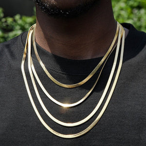 Man wearing layered gold herringbone chains over a black shirt