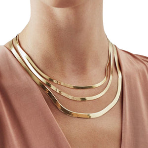 Woman wearing layered yellow gold herringbone chains in different widths