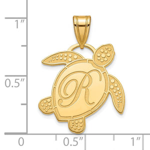 Gold sea turtle initial pendant beside a ruler showing it is under one inch wide