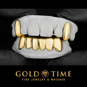 Yellow gold grillz set with two solid top canine fangs and a solid bottom six, shown on dental molds