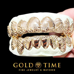 Two tone 16 piece trillion cut grillz set held in a hand on top and bottom dental models