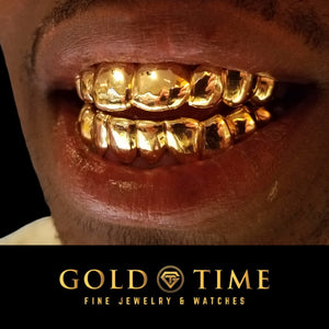 Smiling man wearing a full solid gold top and bottom grillz set