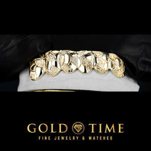 Six piece gold grillz with a nugget texture and diamond dust finish on a dental mold