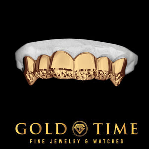 Rose gold six piece grillz with trillion cut tips and canine fangs on a dental model