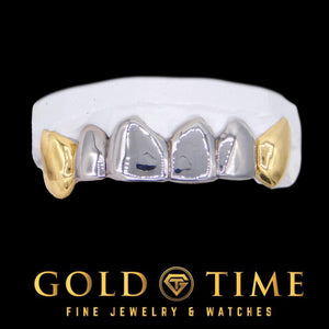 Six piece two-tone grill on a dental mold with white center teeth and yellow gold canines