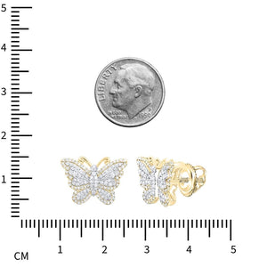 Yellow gold diamond butterfly studs on a ruler next to a dime