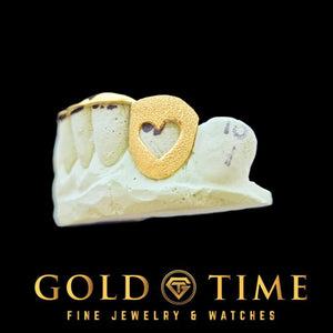 Side view of yellow gold heart cut-out canine grillz with solid center tips on a mold