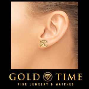 Ear wearing a yellow gold interlocking initial stud earring on a black Gold Time card