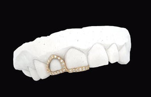 Angled view of yellow gold open face canine cap lined with moissanite stones connected to an iced incisor tip