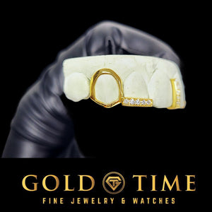 Yellow gold open face canine with a moissanite lateral tip bar on a dental mold held in a gloved hand, Gold Time