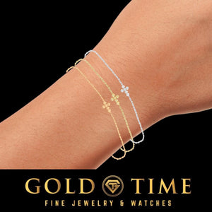 Wrist wearing the gold plated diamond cross bracelet layered with a second chain, on a black Gold Time card