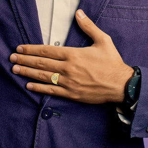 Man in a navy suit jacket wearing a two-tone gold eagle ring on his ring finger