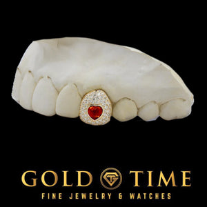 Yellow gold single cap grill iced with moissanite around a red CZ heart, shown on a dental mold