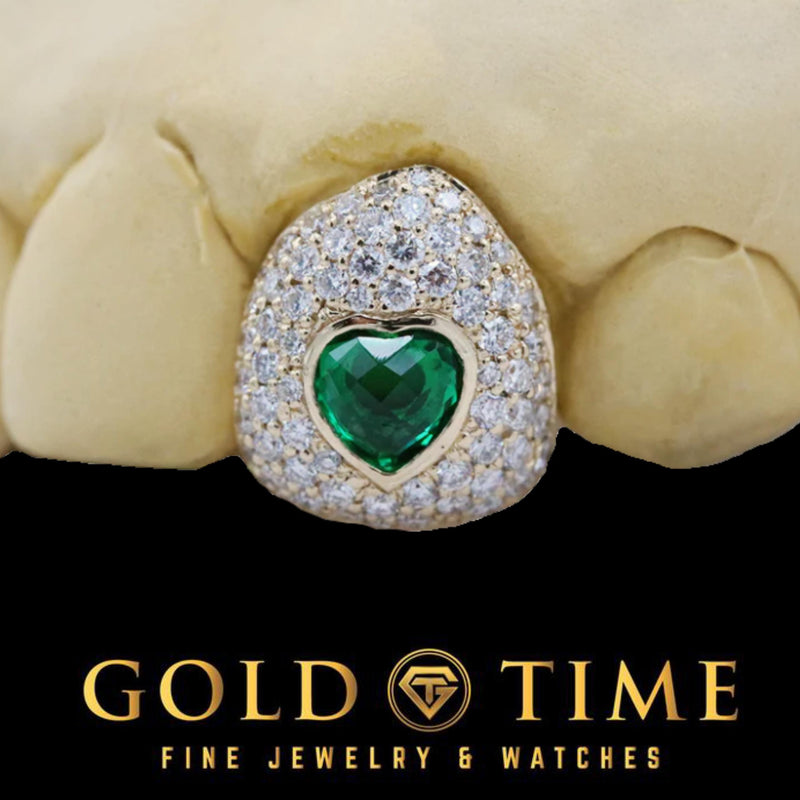 Close-up of a moissanite bustdown cap with a bezel-set green CZ heart in yellow gold