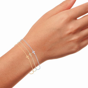 Wrist wearing the sterling silver diamond cross bracelet layered with a second chain