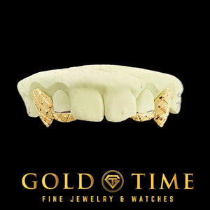 Front view of gold diamond-cut fang grillz on a mold