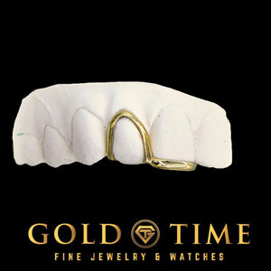 Yellow gold double cap grill with a bottomless open face canine and a solid tip on a mold