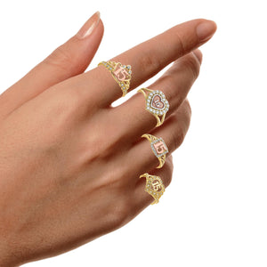 Hand wearing several quinceanera rings including tri-color and CZ heart designs