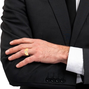 Man in a dark suit wearing a yellow gold diamond cross ring