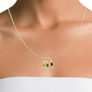 Woman wearing a gold chain with three boy birthstone charms, a family keepsake necklace