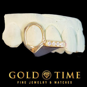 Close up of yellow gold open face canine fang cap connected to a channel of moissanite stones on the incisor tip