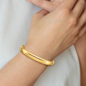 14K gold oval hinged bangle worn on a wrist
