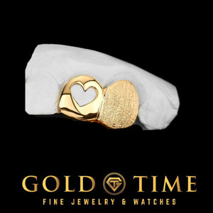 Yellow gold double cap grill with an open heart cutout and a diamond dust cap on a dental mold