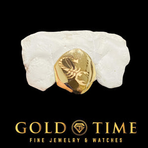 Yellow gold single tooth cap engraved with a scorpion design, fitted to a dental mold