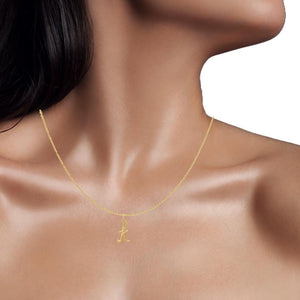 Woman wearing a tiny yellow gold lowercase script initial charm on a thin gold chain