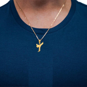 Person wearing a small gold karate kick pendant on a fine gold chain