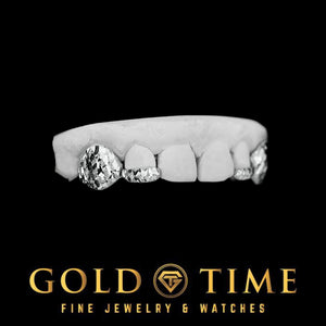 Silver 4 piece trillion cut grillz held in a gloved hand on a labeled dental model