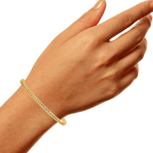 Yellow gold Miami Cuban bracelet worn on a wrist with the hand turned to the side