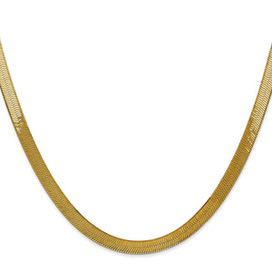 Flat 14k yellow gold herringbone chain lying in a smooth curve