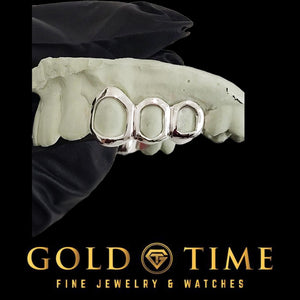 Silver open face triple cap grillz on a dental mold held in a gloved hand, angled view, Gold Time