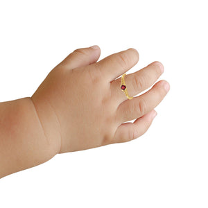 Child's hand wearing a small 14k gold birthstone ring